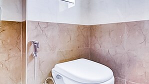 A modern bathroom with a wall-mounted toilet, a shower, and a window providing natural light. - Roomshala 118 Hotel Acclaim 7 sky (New Delhi)