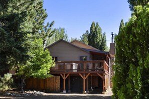 A two-story house with a wooden deck, garage, and surrounded by trees.