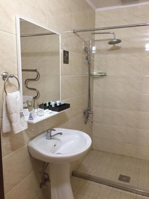 A bathroom with a sink, mirror, towel rack, and a shower with a handheld showerhead.