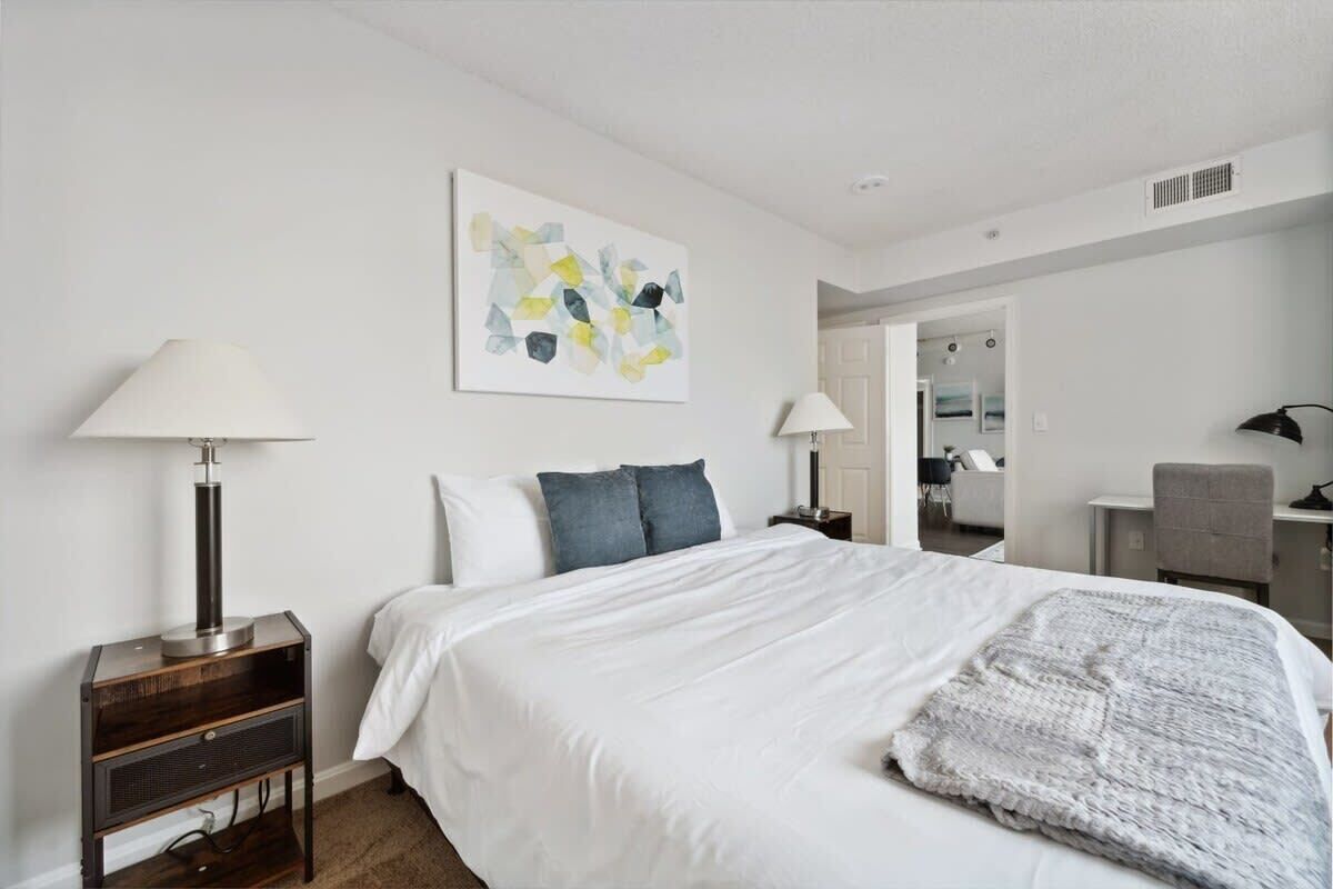 Une chambre à coucher avec un lit, deux tables de chevet, une lampe, un tableau et un miroir.