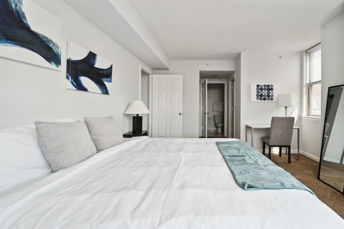 Une chambre d’hôtel moderne, dotée d’un grand lit, d’un bureau et d’une chaise.