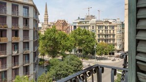Ein mehrstöckiges Gebäude mit Balkonen, eine von Bäumen gesäumte Straße und ein Turmdrehkran im Hintergrund.