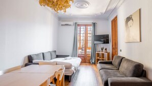 Ein modernes Hotelzimmer mit einer Couch, einem Bett, einem Esstisch und einem Fernseher.