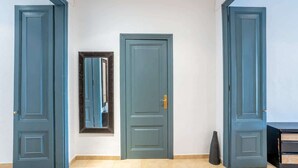 A hallway with three doors, a mirror, and a vase on the floor. - Private terrace Attico 3BD in Gran de Gracia (Barcelona)