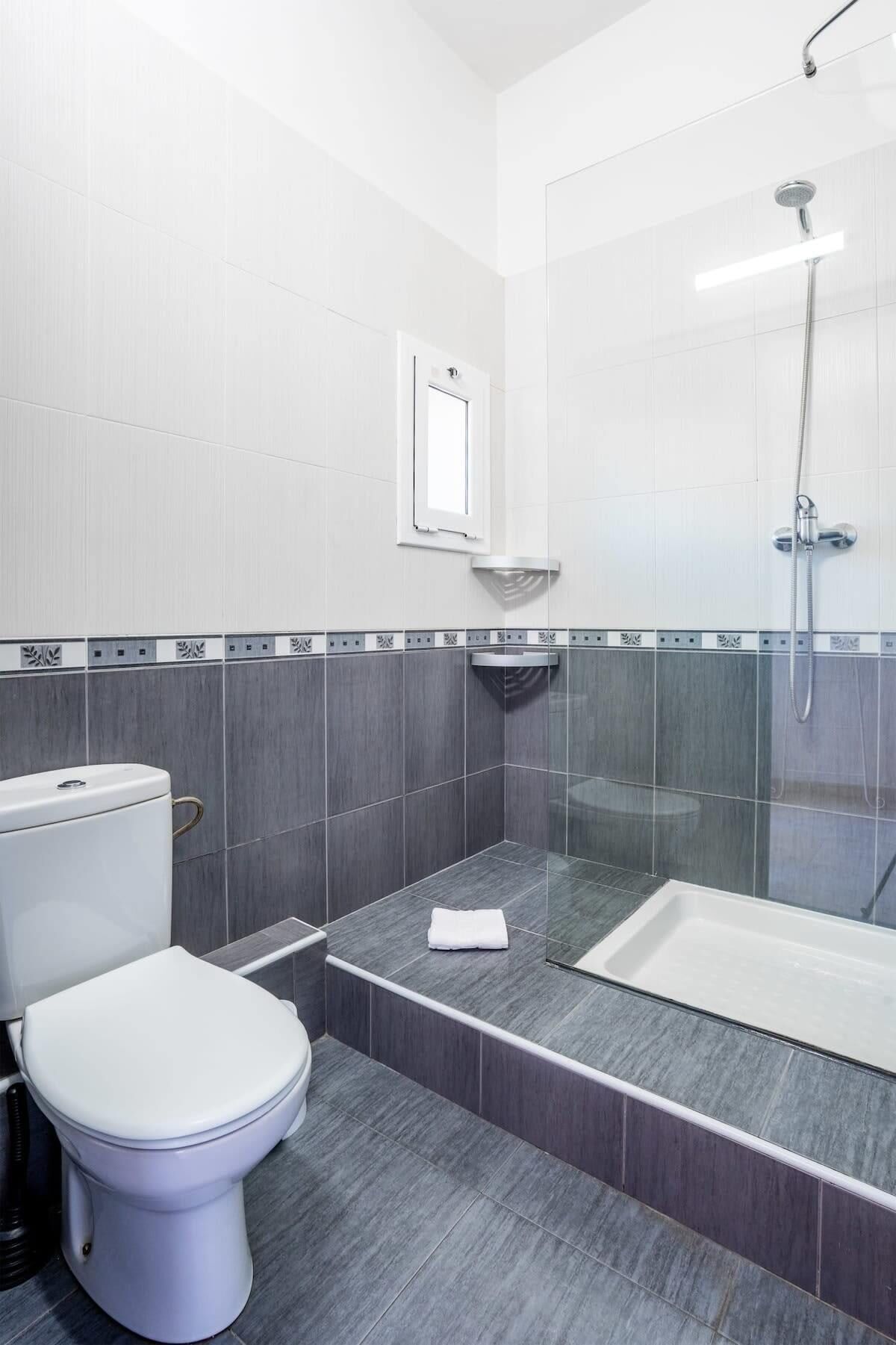 A modern bathroom with a toilet, a shower, and a bathtub.