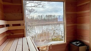 Una cabana de fusta amb una banca i una finestra que dona a un llac.