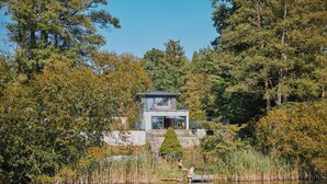 Una casa moderna al costat d'un llac envoltat d'arbres.