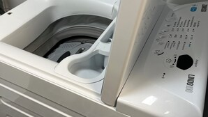 A front view of a white laundry machine with control panel and a small storage compartment. - 05 Central & quiet with SmartTV (Fellbach)