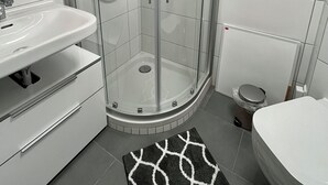 A modern bathroom with a glass-enclosed shower, a sink, and a toilet. - 05 Central & quiet with SmartTV (Fellbach)