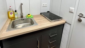 A compact kitchen with a stainless steel sink, wooden countertop, black cabinets, and a built-in induction cooktop. - 05 Central & quiet with SmartTV (Fellbach)