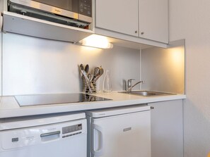 Una cocina compacta equipada con lavavajillas, pileta y microondas.