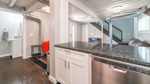 Une cuisine moderne dotée d’appareils électroménagers en acier inoxydable, de meubles blancs et d’un plan de travail en granit.