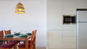 Una cocina moderna con armarios blancos, microondas integrado y un refrigerador de acero inoxidable.