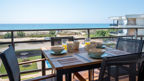 Una mesa preparada para el desayuno con vista a la playa y el océano.