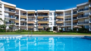 Un hotel moderno de varios pisos con balcones, piscina y zonas de estar al aire libre.