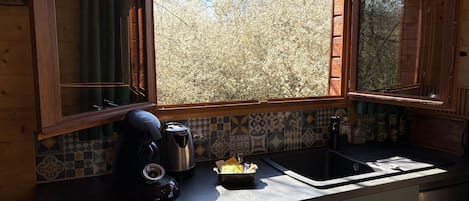 A kitchen with a window, a kettle, a coffee maker, and a sink.