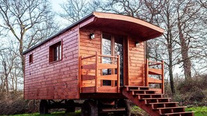 Eine Holzhütte mit gewölbtem Dach, einer Treppe zum Eingang und einem kleinen Fenster an der Seite.
