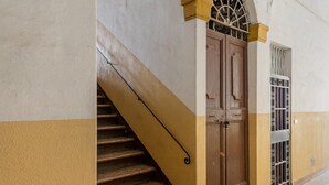 A staircase leading to a door with a metal gate, a doormat, and a textured floor. - Casa sul Canale di Via Piella by Wonderful Italy (Bologna)