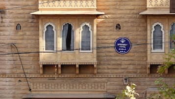 A building with traditional architecture, featuring arched windows and decorative elements. A signboard indicates the name "STEPWELL HOTEL" and a price range of 19-20C.