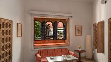 A room with a traditional design, featuring a bench, a table, and a window with a view of the outside.