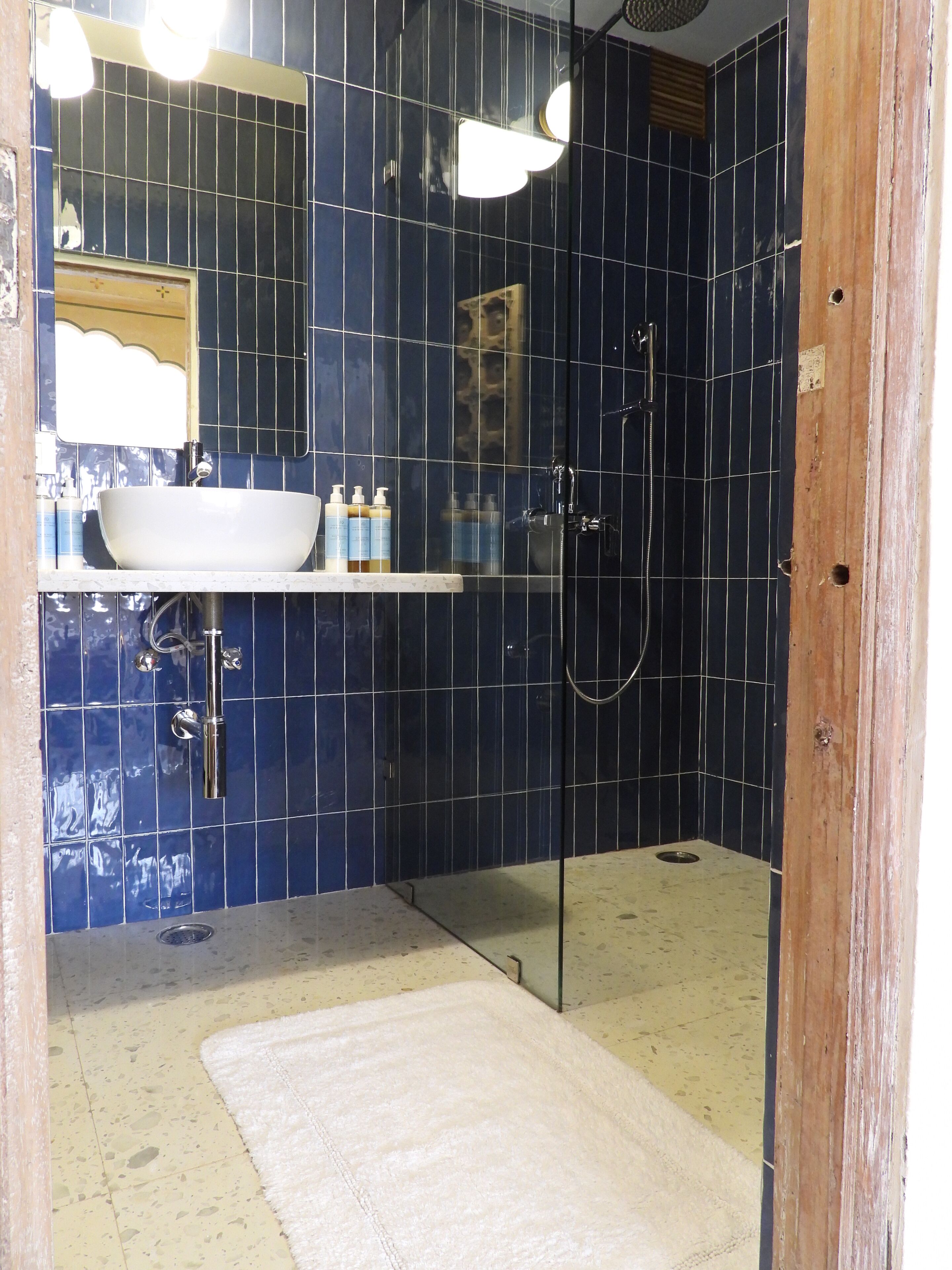 Un baño con lavamanos blanco, espejo y ducha.