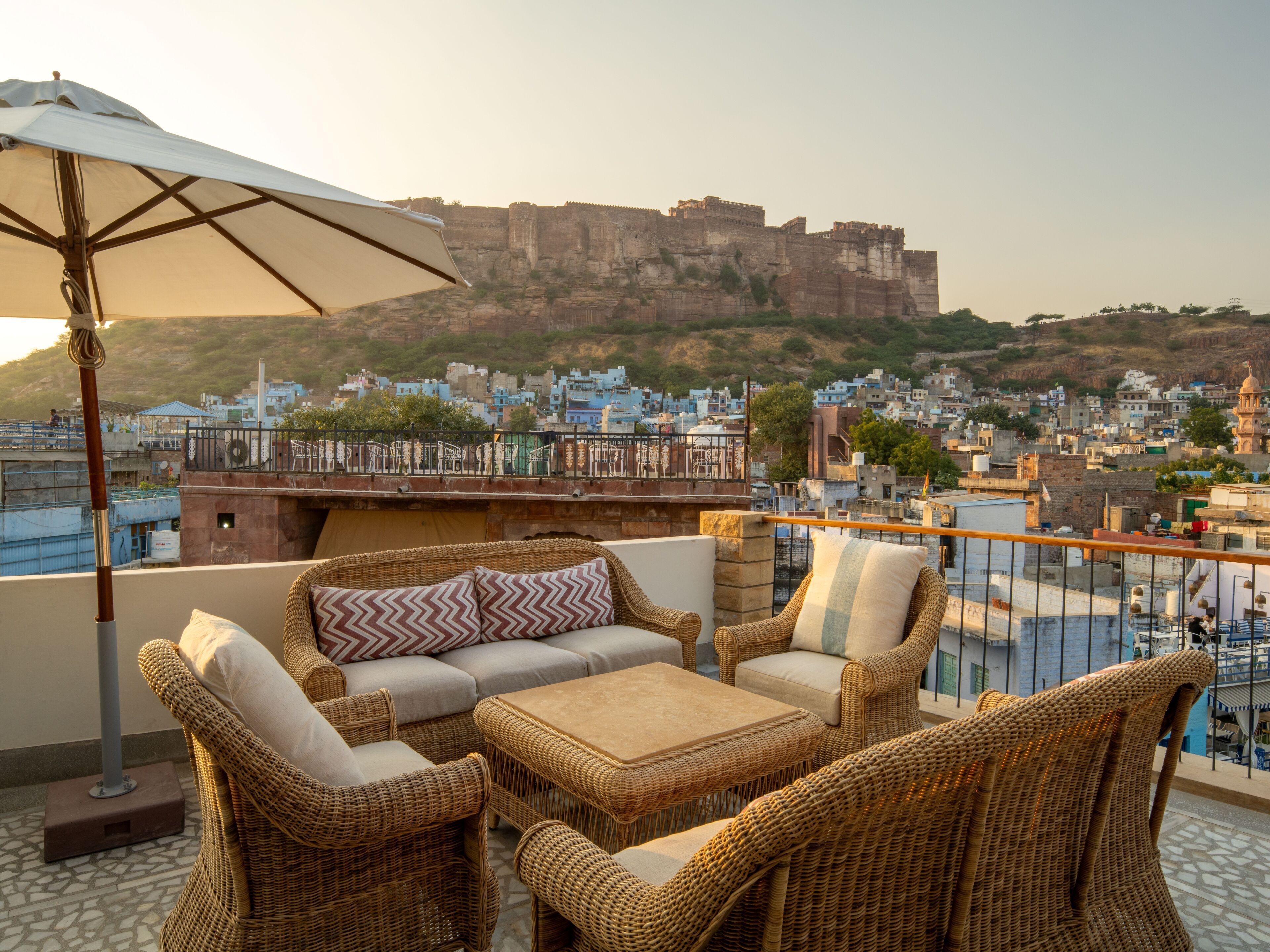 A terrace with wicker furniture and a view of a historic fort in the background.