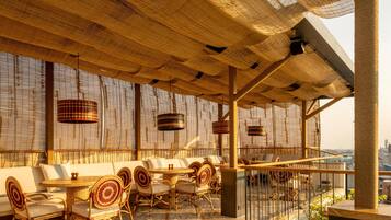 An outdoor seating area with wicker furniture and a view of the city.
