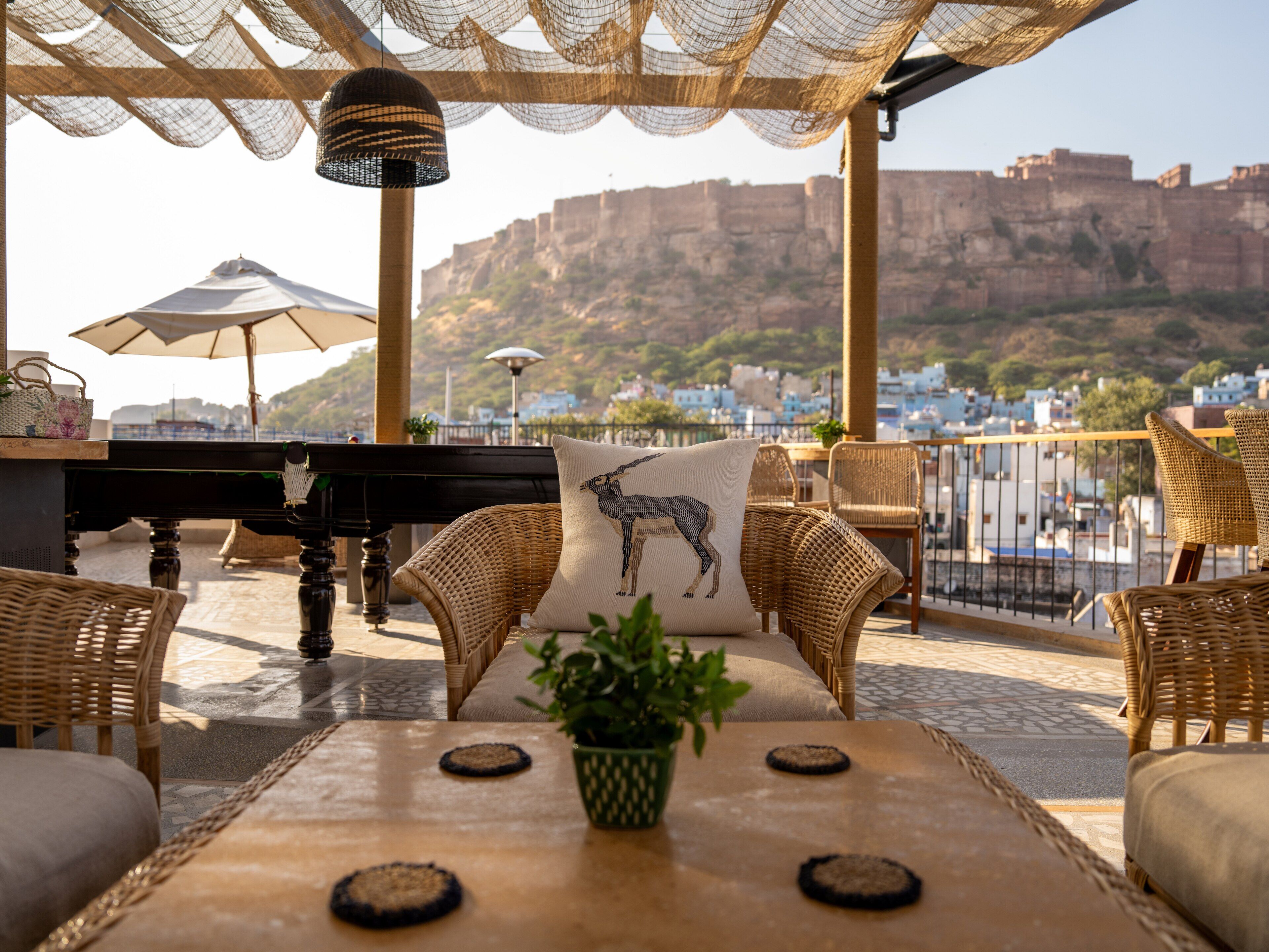 An outdoor seating area with wicker furniture, a piano, and a view of a mountainous landscape.