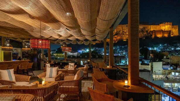 An outdoor seating area with wicker furniture and a view of a cityscape at night.