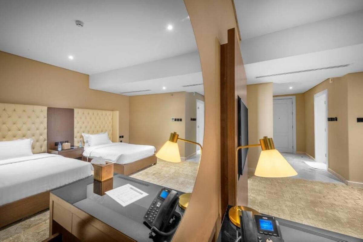 Una habitación de hotel con dos camas, un escritorio y un teléfono, y un televisor.