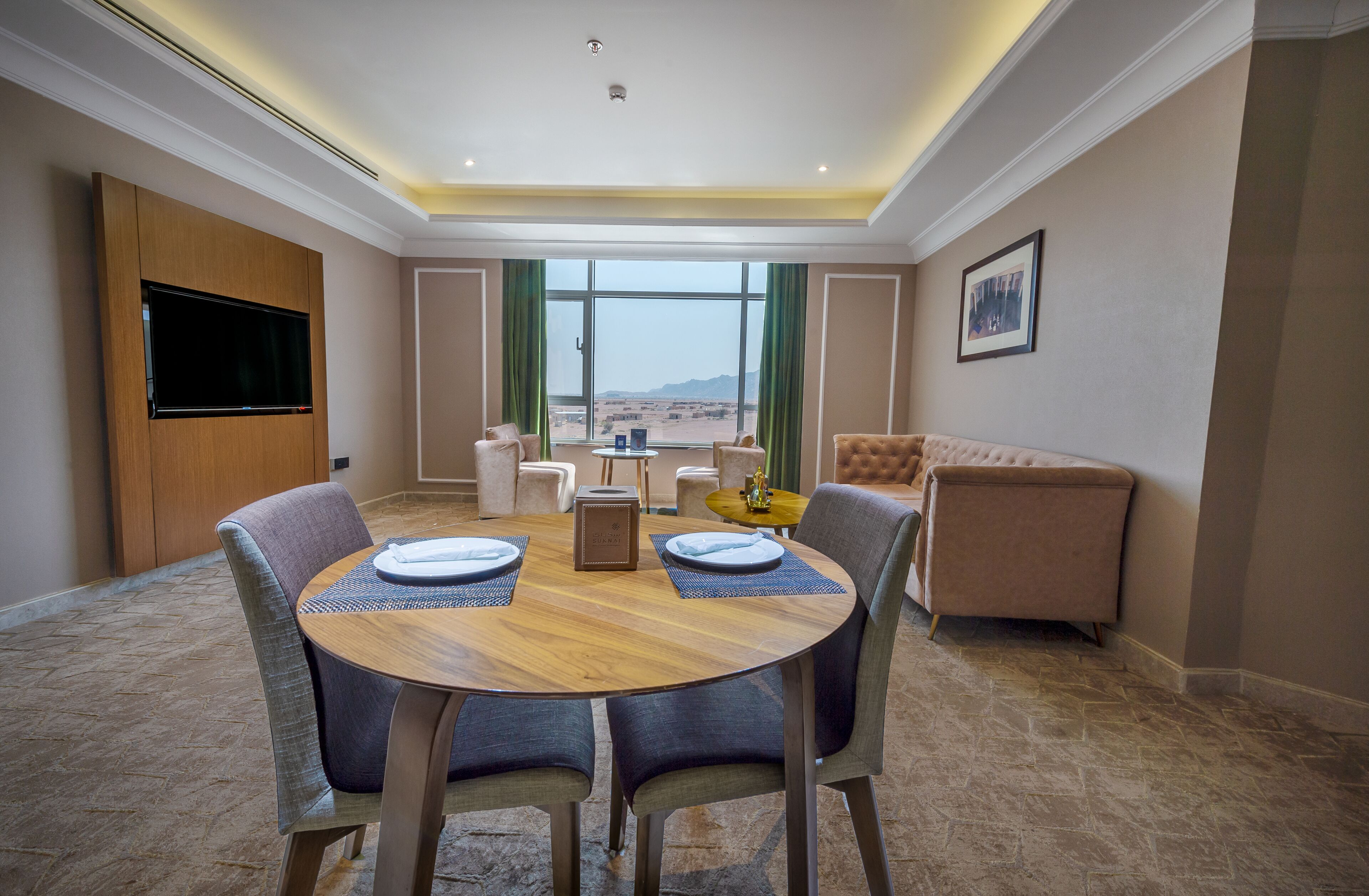 A dining area with a round table, chairs, and a television on the wall.