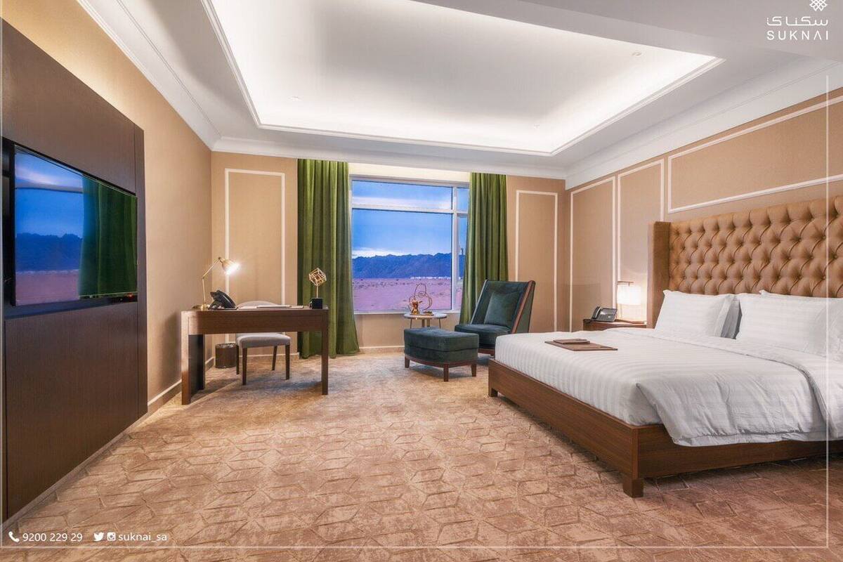 Una habitación de hotel con una cama grande, un escritorio, una silla y un televisor.