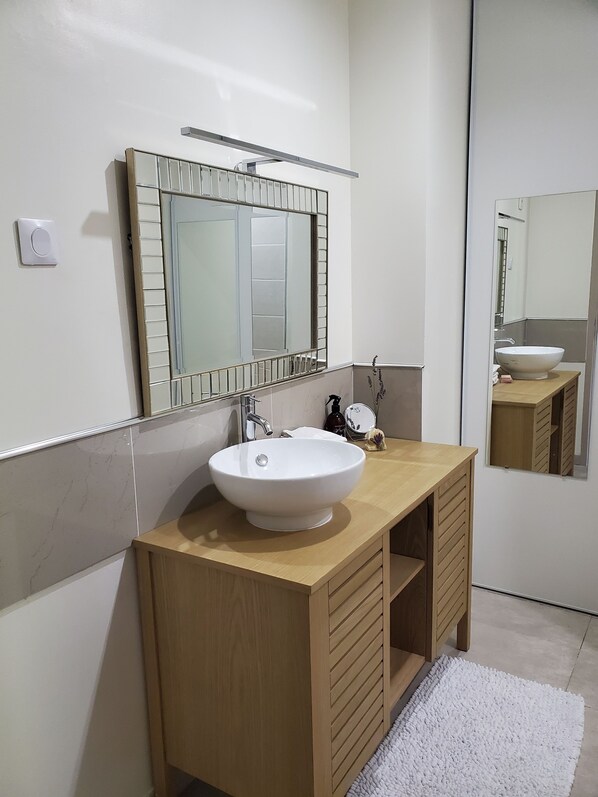 A modern bathroom with a white sink, wooden vanity, and a large mirror above the sink. - Peaceful home with large covered south-facing terrace (Saint-Hippolyte-du-Fort)