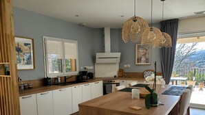 Eine moderne Küche mit weißen Schränken, einer Holzinsel und einem Essbereich mit Tisch und Stühlen.