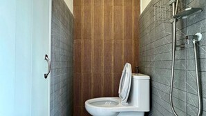 A compact bathroom with a toilet, shower, and a towel rack. - Pure Daily - ห้องพักรายวัน Small and Cozy Rooms for Rest (Mueng Samut Prakan,Theparak)