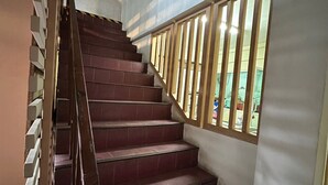 A staircase with wooden railings and red-tiled steps leading to a landing. - Pure Daily - ห้องพักรายวัน Small and Cozy Rooms for Rest (Mueng Samut Prakan,Theparak)