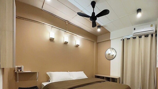 A hotel room with a bed, a desk, a chair, a ceiling fan, and a wall-mounted light fixture. - Pure Daily - ห้องพักรายวัน Small and Cozy Rooms for Rest (Mueng Samut Prakan,Theparak)