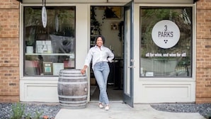 A storefront with a sign reading "3 PARKS all for wine, and wine for all!" and a person standing next to a barrel. - Splash Pad (Atlanta)