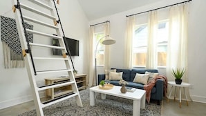 A living room with a white ladder, a blue sofa, a white coffee table, and a patterned rug. - Splash Pad (Atlanta)