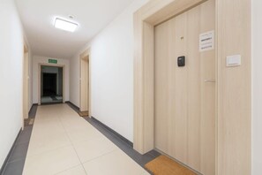 A hallway with a wooden door labeled "RENTERS5X" and a sign indicating a "Muscle" room.