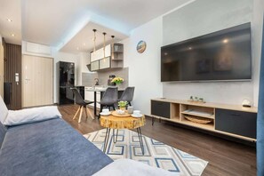 Ein modernes Wohnzimmer mit einer Couch, einem Esstisch, Stühlen und einem Fernseher.