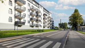 A multi-story residential building with balconies, a pedestrian crossing, and a clear sky. - Stylish Apartment with Balcony | Parking in Garage (Świnoujście)