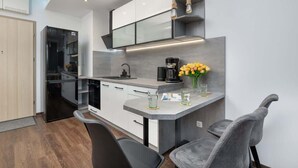 A modern kitchen with a central island, black appliances, and a minimalist design. - Stylish Apartment with Balcony | Parking in Garage (Świnoujście)