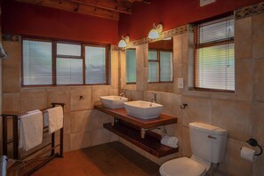 A bathroom with two sinks, a toilet, and a towel rack.