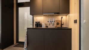 A modern kitchen with a built-in oven, a coffee machine, and utensils hanging on the wall.