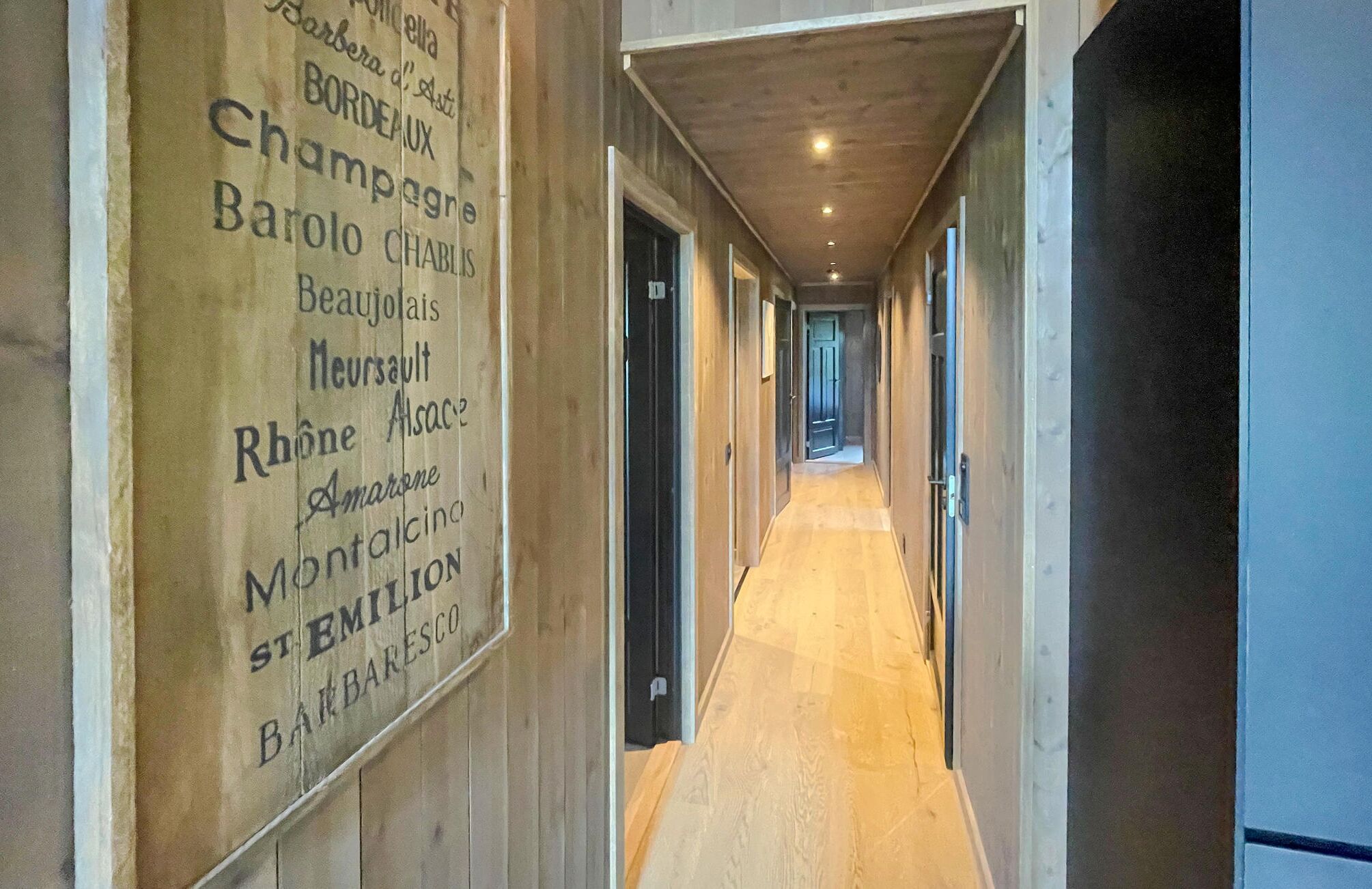 A hallway with wooden walls and a light wooden floor.