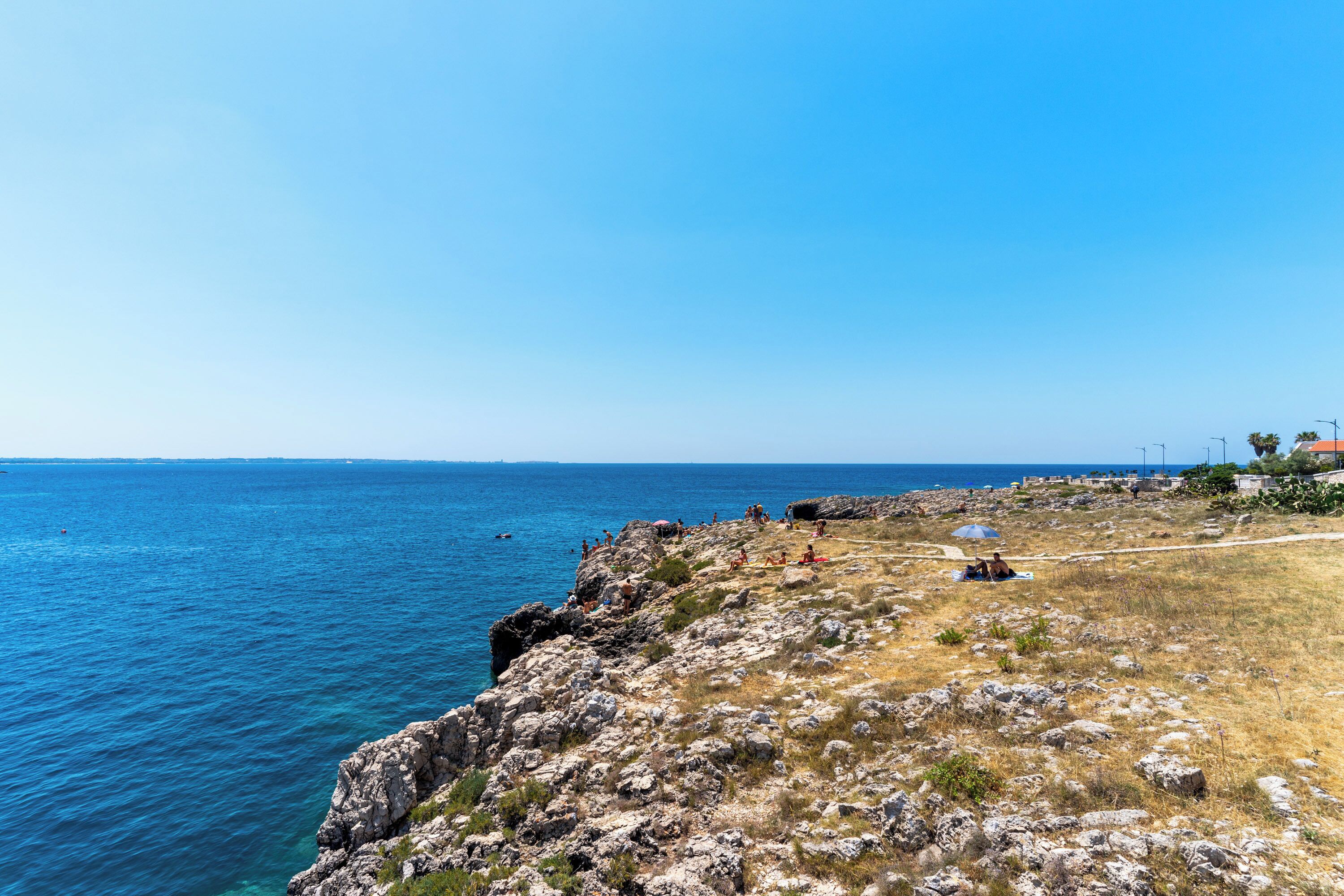 A coastal landscape with rocky terrain and a clear view of the sea.