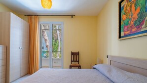 Quarto com cama, uma cadeira, guarda-roupa e um quadro na parede.