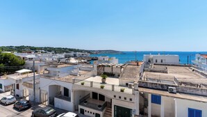 Uma vila costeira com edifícios brancos, um céu azul límpido e vista para o mar.