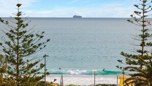 A beach with waves, a distant ship, and trees framing the view. - Apartment M204 - coastal and comfortable! (Scarborough)